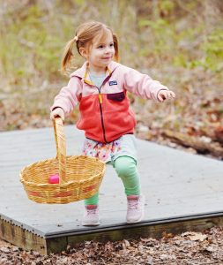 young child gathering eggs in the woods at the Nature Center